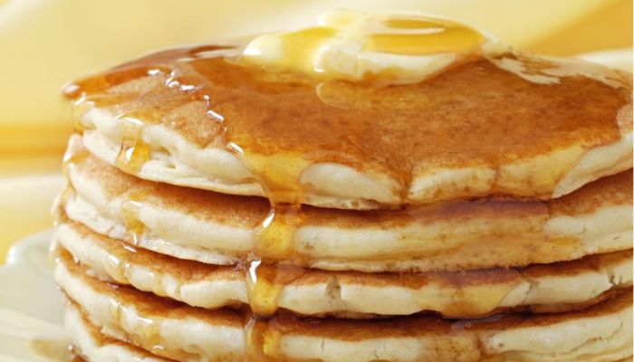 Imagem de panquecas americanas douradas, cobertas com mel e manteiga, representando a perfeição do café da manhã.